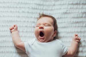 baby yawning while laying in a crib